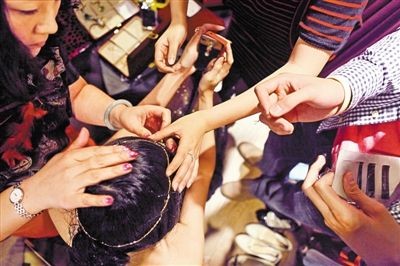 Tại một buổi diễn thời trang ở Long Cương, các chuyên gia làm tóc và stylist tấp nập hóa trang cho một người mẫu trước giờ diễn.